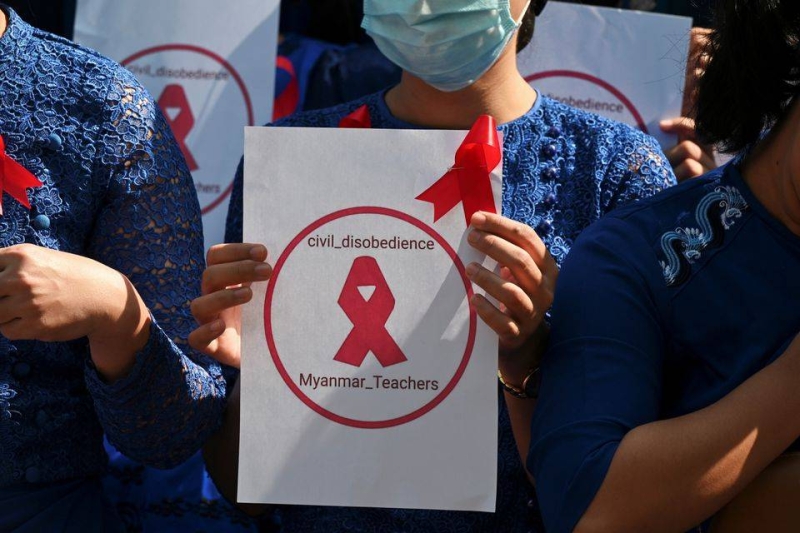 A teacher from Yangon University of Education holds a sign with a red ribbon while taking part in a demonstration against the military coup in Yangon, Myanmar, February 5, 2021. Photo: Reuters
