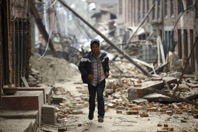 A man runs past damaged houses as aftershocks of an earthquake are felt a day after the earthquake in Bhaktapur, Nepal April 26, 2015. REUTERS/Navesh Chitrakar