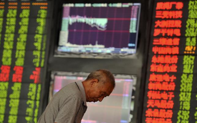 An investor looks down in front of an electronic board showing stock information at a brokerage house in Fuyang, Anhui province, China, June 29, 2015. REUTERS/Stringer