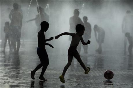 Children play soccer as they cool down in a fountain beside Manzanares river in Madrid, Spain, Monday, June 29, 2015. Weather stations across Spain are warning people to take extra precautions as a heat wave engulfs much of the country, increasing the risk of wildfires. AP
