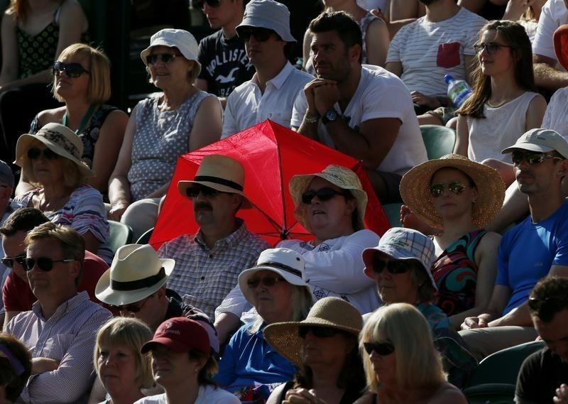 A couple shelter from the sun with a red umbrella at the Wimbledon Tennis Championships in London, June 29, 2015.   REUTERS/Stefan Wermuth