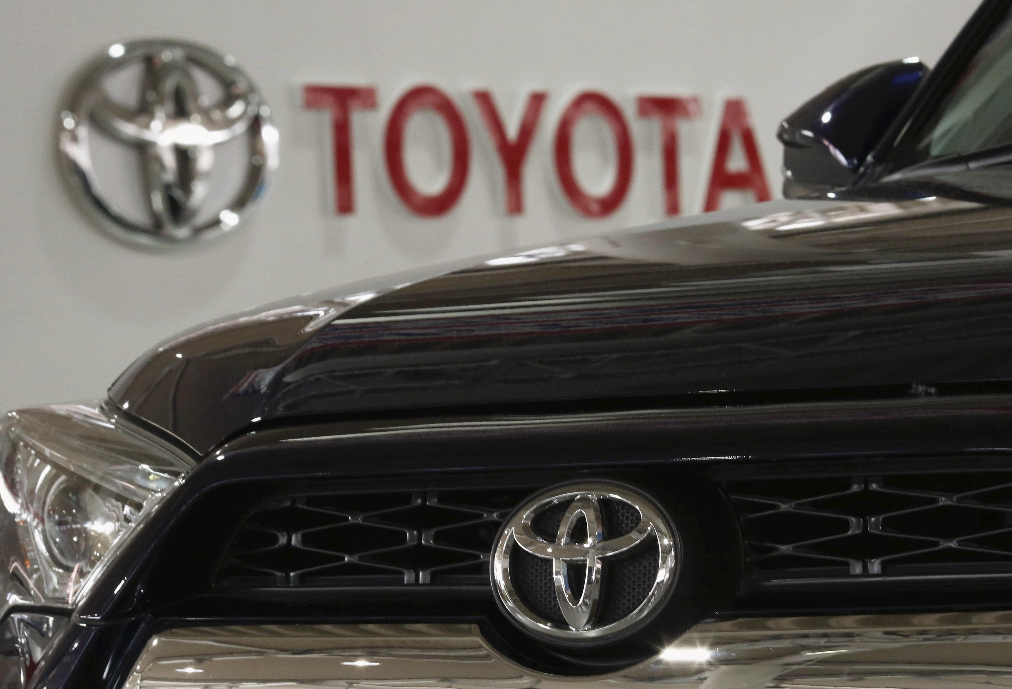 A logo of Toyota Motor Corp is pictured on a car and the background at the company's showroom in Tokyo, Japan, June 16, 2015. Toyota Motor Corp shareholders approved a controversial new class of stock on Tuesday that will bring in more long-term investors, but which faced opposition from foreign funds as they are readily available only in Japan. REUTERS/Yuya Shino