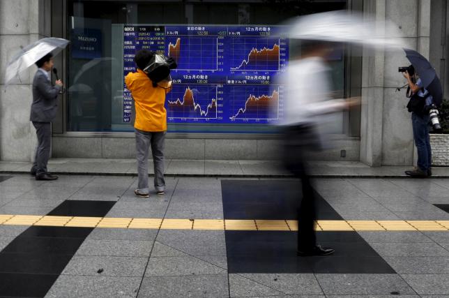 Videographer films an electronic board showing the graphs of exchange rates between the Japanese yen, the U.S. dollar and Euro outside a brokerage in Tokyo, Japan, July 6, 2015.  REUTERS/Yuya Shino