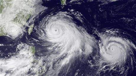 This satellite image taken by the JMA MTSAT-2 satellite at 9;30 a.m. EDT on Thursday, July 9, 2015, shows Tropical Storm Linfa, left, tracking westward parallel to the coast of China, and Typhoon Chan-hom, over the Ryukyu Trench south of Okinawa, Japan, on a track heading northwest toward the China coast north of Wenzhou. Southeastern provinces in China were alerted about possible flooding and severe weather this week from both approaching storms. AP