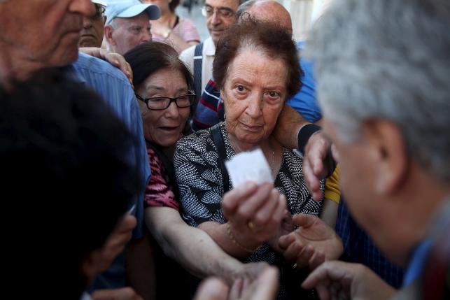 Pensioners are given priority tickets by a National Bank branch manager as they wait to receive part of their pensions in Athens, Greece July 16, 2015.  Photo: Reuters