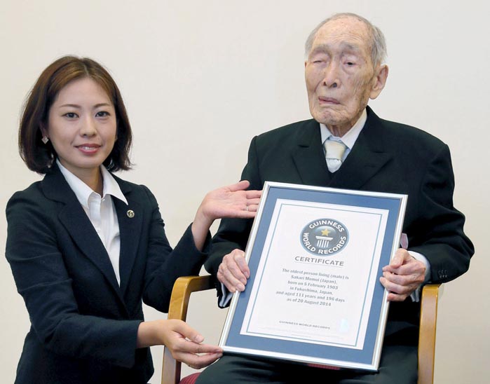Sakari Momoi (R) receives a Guinness World Records certificate naming him as the world's oldest man at 111 years of age, in Tokyo, in this photo taken by Kyodo August 20, 2014. Momoi, who was recognised as the world's oldest man and credited healthy eating and getting plenty of sleep for his longevity, has died at the age of 112, Japanese media said on July 7, 2015. Picture taken August 20, 2014. Mandatory credit REUTERS/Kyodo    TPX IMAGES OF THE DAY     nnATTENTION EDITORS - THIS IMAGE HAS BEEN SUPPLIED BY A THIRD PARTY. FOR EDITORIAL USE ONLY. NOT FOR SALE FOR MARKETING OR ADVERTISING CAMPAIGNS. JAPAN OUT. NO COMMERCIAL OR EDITORIAL SALES IN JAPAN. MANDATORY CREDIT. THIS PICTURE WAS PROCESSED BY REUTERS TO ENHANCE QUALITY. AN UNPROCESSED VERSION WILL BE PROVIDED SEPARATELY.tntn      TPX IMAGES OF THE DAY