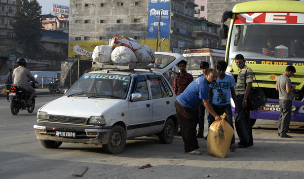 File - A taxi driver helping load the belongings of a passenger, in Kalanki, Kathmandu, on Friday, July 3, 2015. Photo: THT