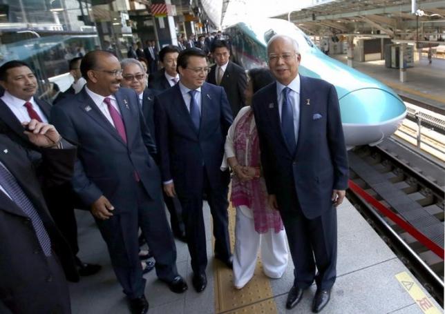 Malaysia's Prime Minister Najib Razak (R), accompanied by his wife Rosmah Mansor, smiles before he boards to a Shinkansen bullet train (behind Najib) bound for northern Japan, at Tokyo Station in Tokyo May 26, 2015. REUTERS/Issei Kato/Files