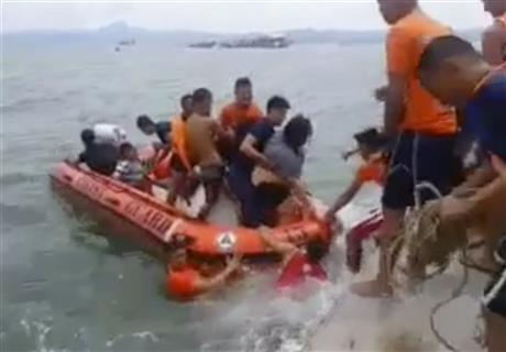In this image made from video, rescuers help passengers from a capsized ferry boat, rear, in Ormoc city on Leyte Island, Philippines, Thursday, July 2, 2015. A ferry capsized Thursday as it left a central Philippine port in choppy waters, leaving at least dozens dead and many others missing, coast guard officials said.  AP