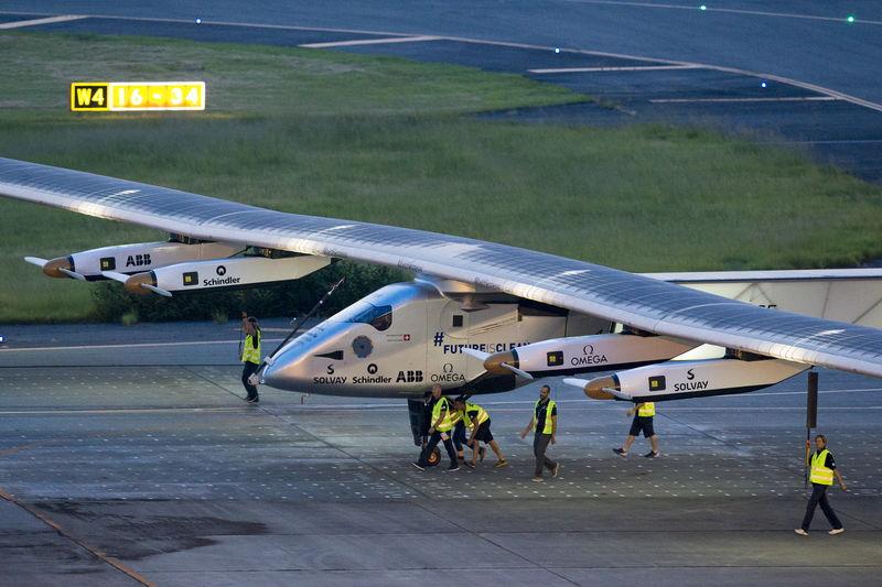 Crew members push the solar-powered plane Solar Impulse 2 to its parking position at Nagoya airport after changing weather conditions thwarted a planned take-off, June 24, 2015.  Photo: Reuters