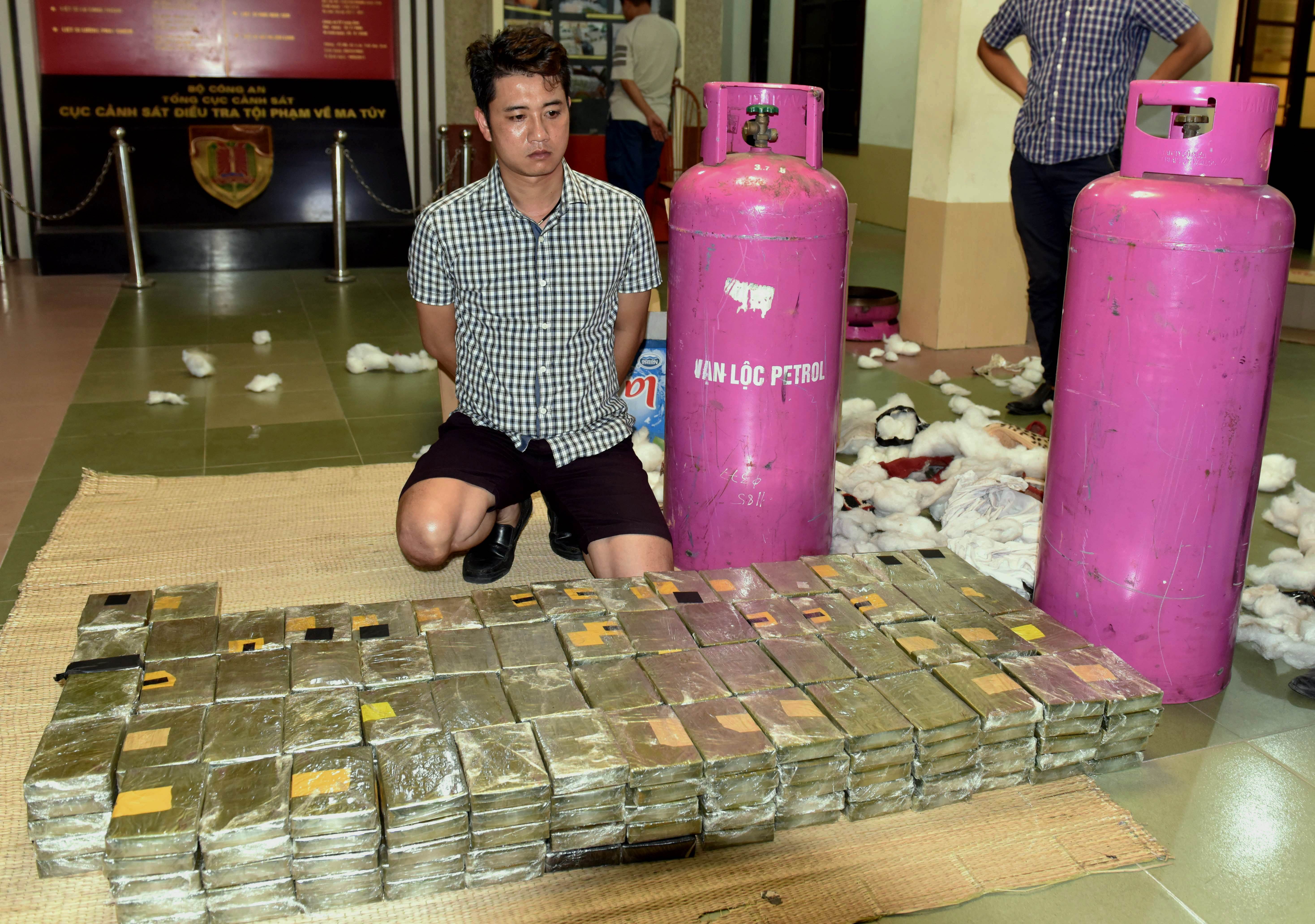 This picture from the Vietnam News Agency taken on July 26, 2015 shows arrested drug trafficker Nguyen Quoc Hung, 32, posing with the seized contraband at the anti-narcotics police department in Hanoi.  Photo: AFP/Vietnam News Agency