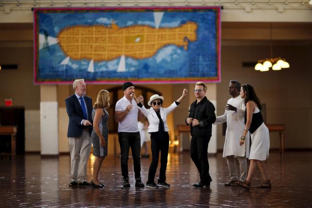 Artist Yoko Ono (C), widow of John Lennon, reacts next to Irish singer Bono (3rd R) and guitarist The Edge of U2 (3rd L) during the unveiling of a tapestry honoring Lennon at Ellis Island in New York July 29, 2015. REUTERS/Eduardo Munoz