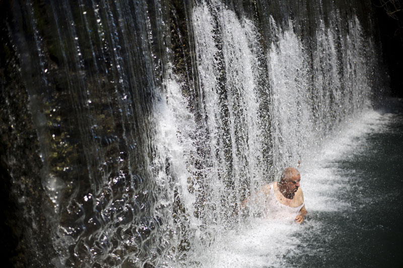 An Arab man cools off under a waterfall at the Gan HaShlosha national park near the northern Israeli Town of Beit Shean, Israel, Thursday, July 30, 2015. Photo: AP