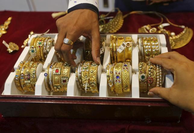 A salesman helps a customer (R) to select gold bangles at a jewelry showroom in Mumbai, May 21, 2015. REUTERS/Shailesh Andrade/Files