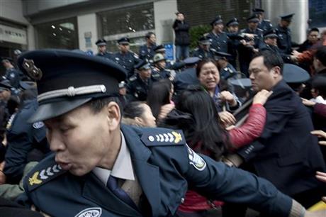 In this March 19, 2015 photo, security guards scuffle with protestors angry about failed investments with Hunan Bofeng Asset Management Ltd. outside of a branch of the Industrial and Commercial Bank of China in Changsha in southern China's Hunan province. AP