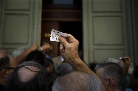 A man holds a tag queue position as he waits next to others pensioners outside the main gate of the national bank of Greece to withdraw a maximum of 120 euros ($134) in central Athens, Friday, July 10, 2015. AP