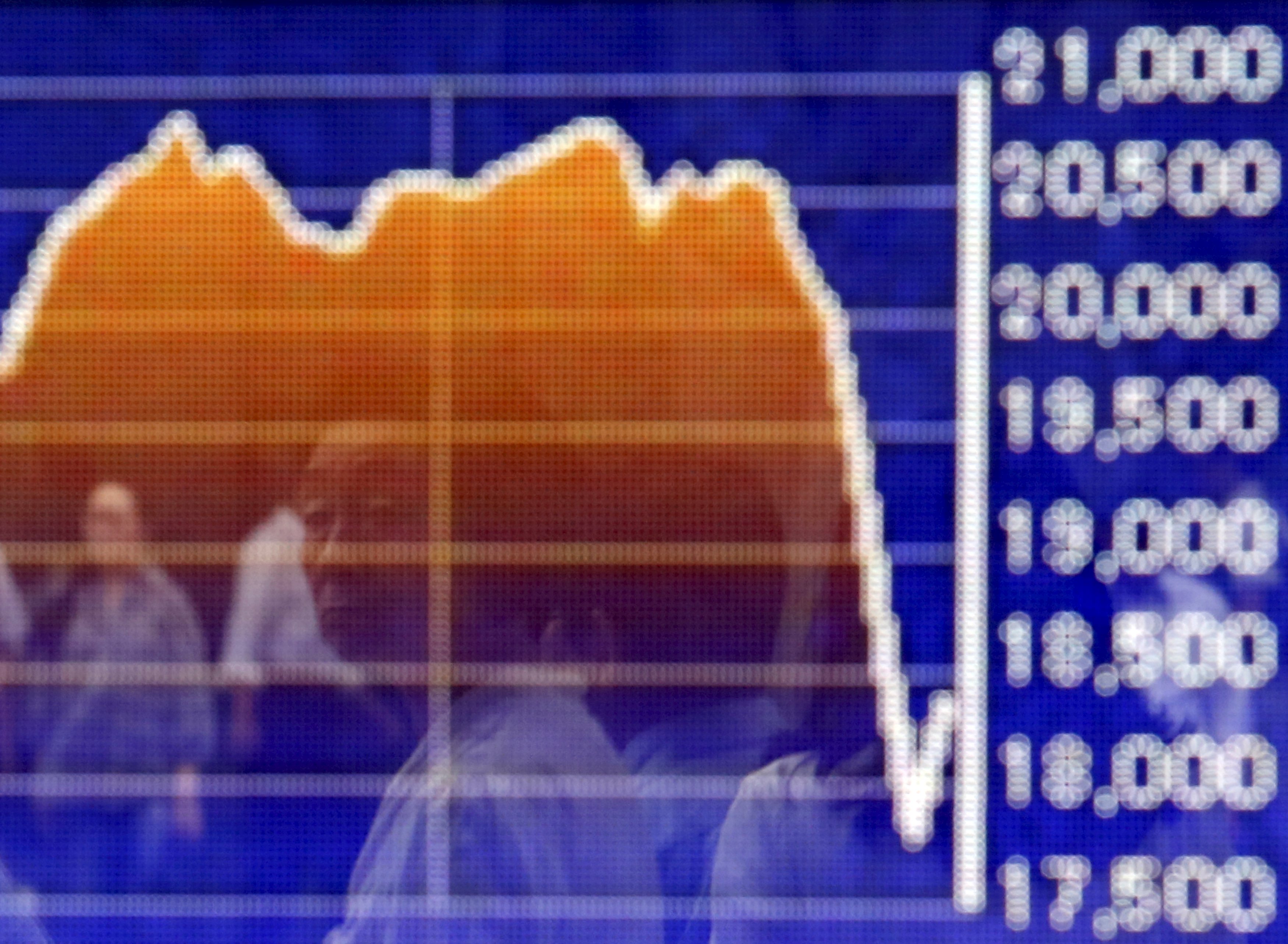 A pedestrian is reflected on an electronic board showing the graph of the recent fluctuations of the Japan's Nikkei average outside a brokerage in Tokyo, Japan, August 27, 2015. Photo: Reuters