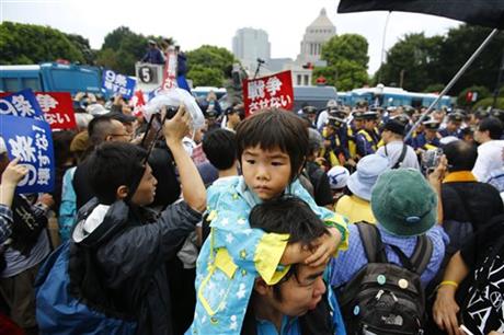 In this photo taken on Sunday, Aug. 30, 2015, a father carries his son on his shoulders during a rally in front of the parliament building in Tokyo. Mothers holding their children's hands stood in the sprinkling rain, some carrying anti-war placards, while students chanted slogans to the beat of a drum against Prime Minister Shinzo Abe and his defense policies. Photo:AP