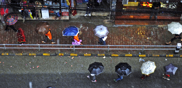 A row of shoppers walking under umbrellas in New Road, Kathmandu, on a rainy Friday.  Photo:THT