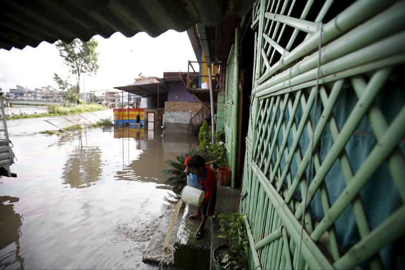 n    A boy uses a bucket to clear floodwaters from a house, which flowed in from the swollen Bagmati River caused by heavy rainfall, in Kathmandu, on August 17, 2015. Photo: Reuters
