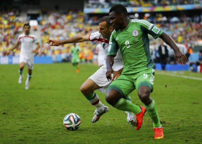 Nigeria's Emmanuel Emenike (front) fights for the ball with Iran's Jalal Hosseini during their 2014 World Cup Group F soccer match at the Baixada arena in Curitiba June 16, 2014. REUTERS/Ivan Alvarado