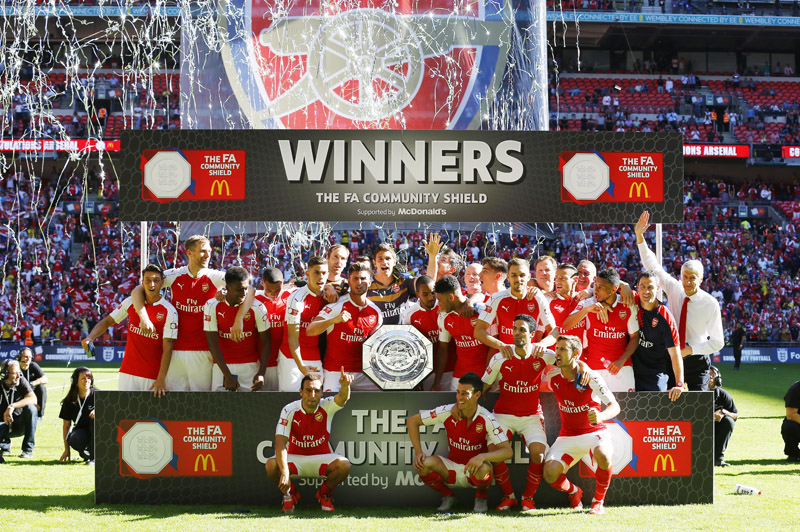 Arsenal's manager Arsene Wenger (right) and his players celebrate with the trophy after beating Chelsea in the FA Community Shield match at Wembley Stadium in north London on Sunday. Arsenal won the match 1-0. Photo: Reuters
