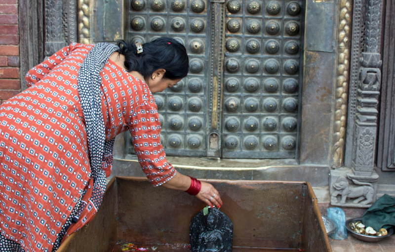 A woman offering holy water to the idol of lord Buddha during Gunla Festival, in Mangalbazaar, Lalitpur, on Saturday. Photo: THT