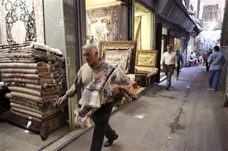 In this Monday, Aug. 10, 2015 photo, an Iranian man carries a carpet through Tehran's old, main bazaar, Iran. Iran's famed carpet weavers are busy at work following the countryu2019s historic nuclear deal with world powers, anticipating a boost in exports as sanctions are set to be lifted in the months ahead. AP