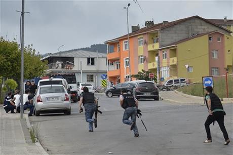 Turkish police officers run for cover during a gunfight near the site of an overnight explosion at a police station in Istanbul's Sultanbeyli neighborhood, Monday, Aug. 10, 2015. The bomb attack at the police station injured three policemen and seven civilians and caused a fire that collapsed part of the three-story building. Police said the assailants exploded a car bomb near the station. Unknown assailants later fired on police inspecting the scene of the explosion, sparking another gunfight with police that killed a member of the police inspection team and two assailants.  Photo: AP