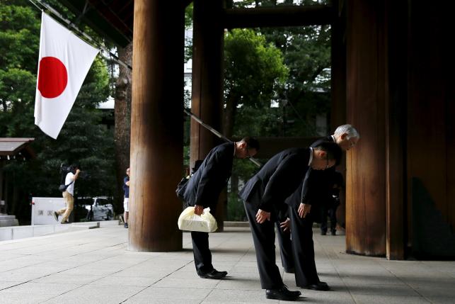 Men bow before entering Yasukuni Shrine on the anniversary of Japan's surrender in World War Two in Tokyo August 15, 2015.  REUTERS/Thomas Peter