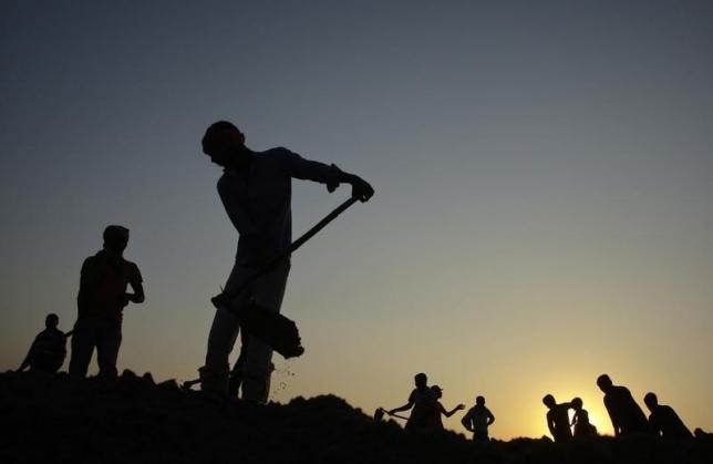 Labourers work on levelling land as the sun sets in Allahabad December 8, 2012. REUTERS/Jitendra Prakash/Files