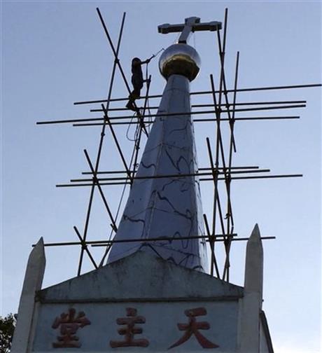 In this July 30, 2015 image taken from video, a cross atop the Lower Dafei Catholic Church topples after being cut down by a Chinese government worker with a cutting torch in Lower Dafei Village in Yongjia County in eastern China's Zhejiang Province. AP