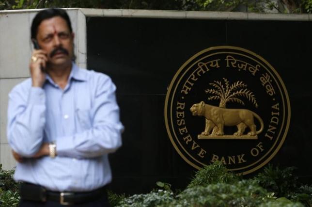 A man speaks on his mobile phone in front of the Reserve Bank of India (RBI) seal at the RBI headquarters in Mumbai July 30, 2013. REUTERS/Vivek Prakash/Files