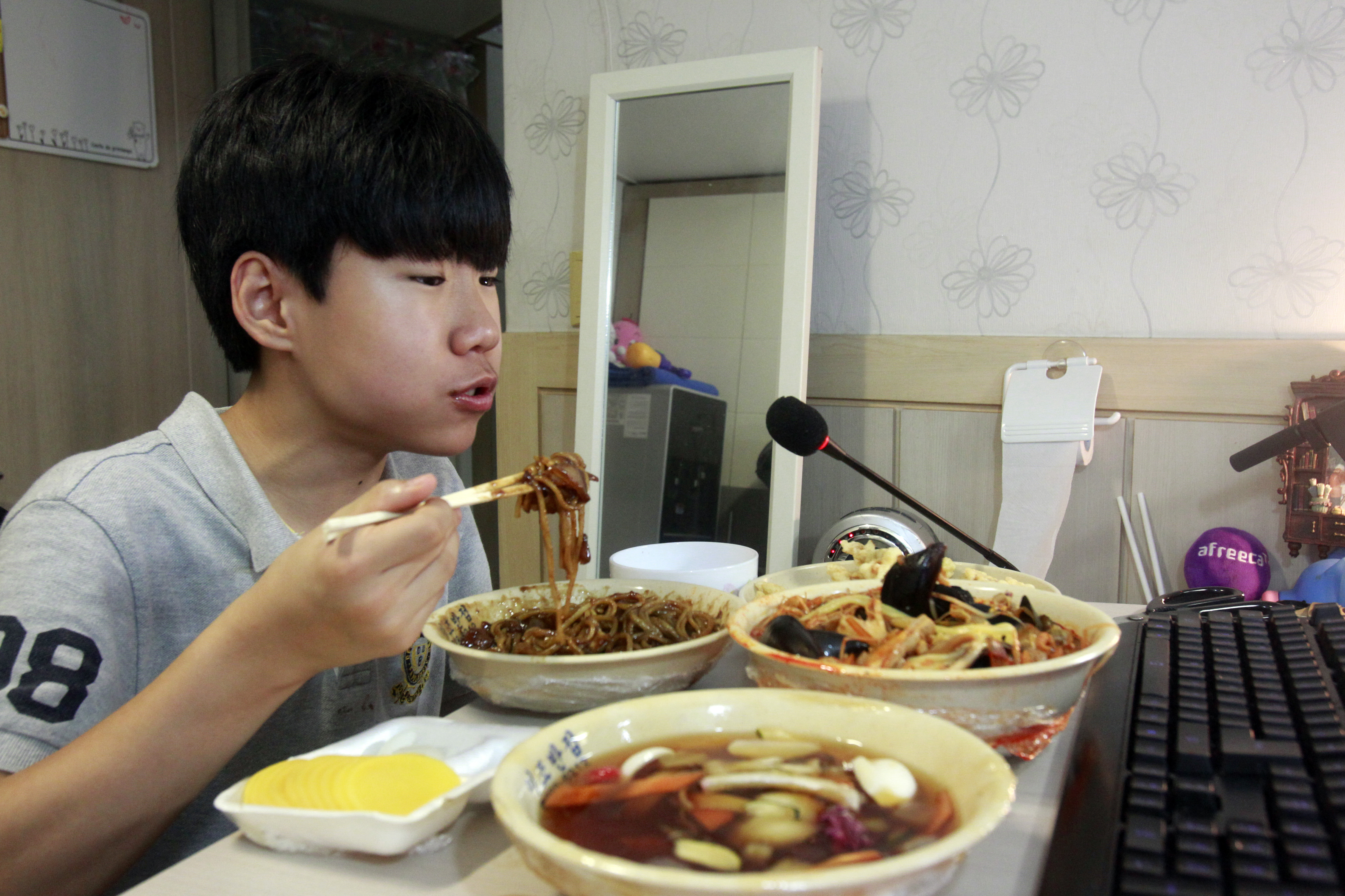 In this Monday, Aug 17, 2015 photo, Kim Sung-jin, 14, broadcasts himself eating delivery Chinese food in his room at home in Bucheon, south of Seoul, South Korea. Every evening, he gorges on food as he chats before a live camera with hundreds, sometimes thousands, of teenagers watching. Thatu0092s the show, and it makes Kim money: 2 million won ($1,700) in his most successful episode. Better known to his viewers by the nickname Patoo, he is one of the youngest broadcasters on Afreeca TV, an app for live-broadcasting video online launched in 2006. Photo: AP