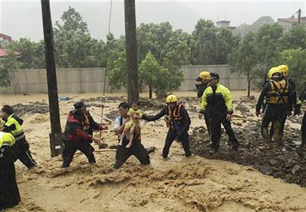 In this image released by the New Taipei Fire Department, emergency rescue personnel carry a child through a flash mudslide caused by Typhoon Soudelor in Xindian, New Taipei City, northern Taiwan, Saturday, Aug. 8, 2015. At least four people were killed and four were missing when powerful Typhoon Soudelor slammed into Taiwan, authorities said Saturday. Photo:AP