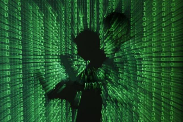 An illustration picture shows a projection of binary code on a man holding a laptop computer, in an office in Warsaw June 24, 2013. Photo: Reuters