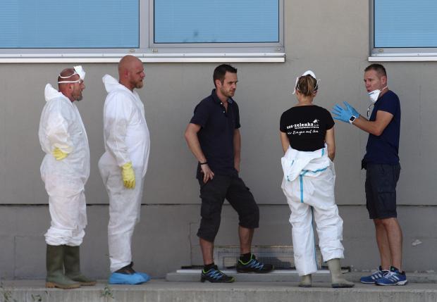 Members of a forensic team talk near a truck in which more than 70 bodies were found, at a customs building with refrigeration facilities in the village of Nickelsdorf, Austria, August 29, 2015. REUTERS/Heinz-Peter Bader