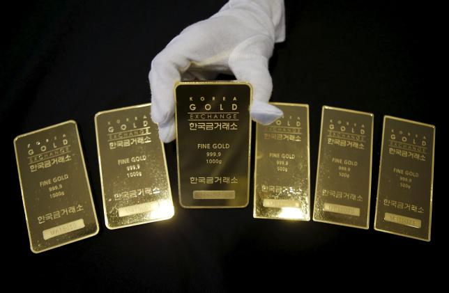 An employee poses for photographs with gold bars at the Korea Gold Exchange in Seoul, South Korea, July 31, 2015. REUTERS/Kim Hong-Ji/Files