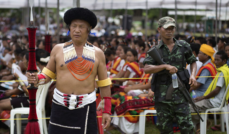 A Naga man in traditional attire and a cadre of Isak-Muivah faction of the National Socialist Council of Nagaland (NSCN-IM) stand guard as they listen to Thuingaleng Muivah, leader of the NSCN-IM during Independence Day celebrations at the councilu2019s headquarters in Hebron, in Indiau2019s north eastern state of Nagaland, Friday, Aug. 14, 2015. Photo: AP 