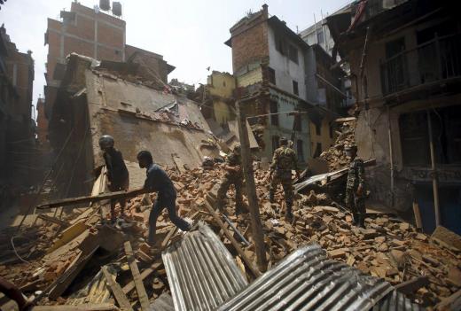 Members of the Nepal Army and locals clear debris after demolishing the remains of collapsed houses, a month after the April 25 earthquake, in Kathmandu, Nepal May 29, 2015. Photo: Reuters