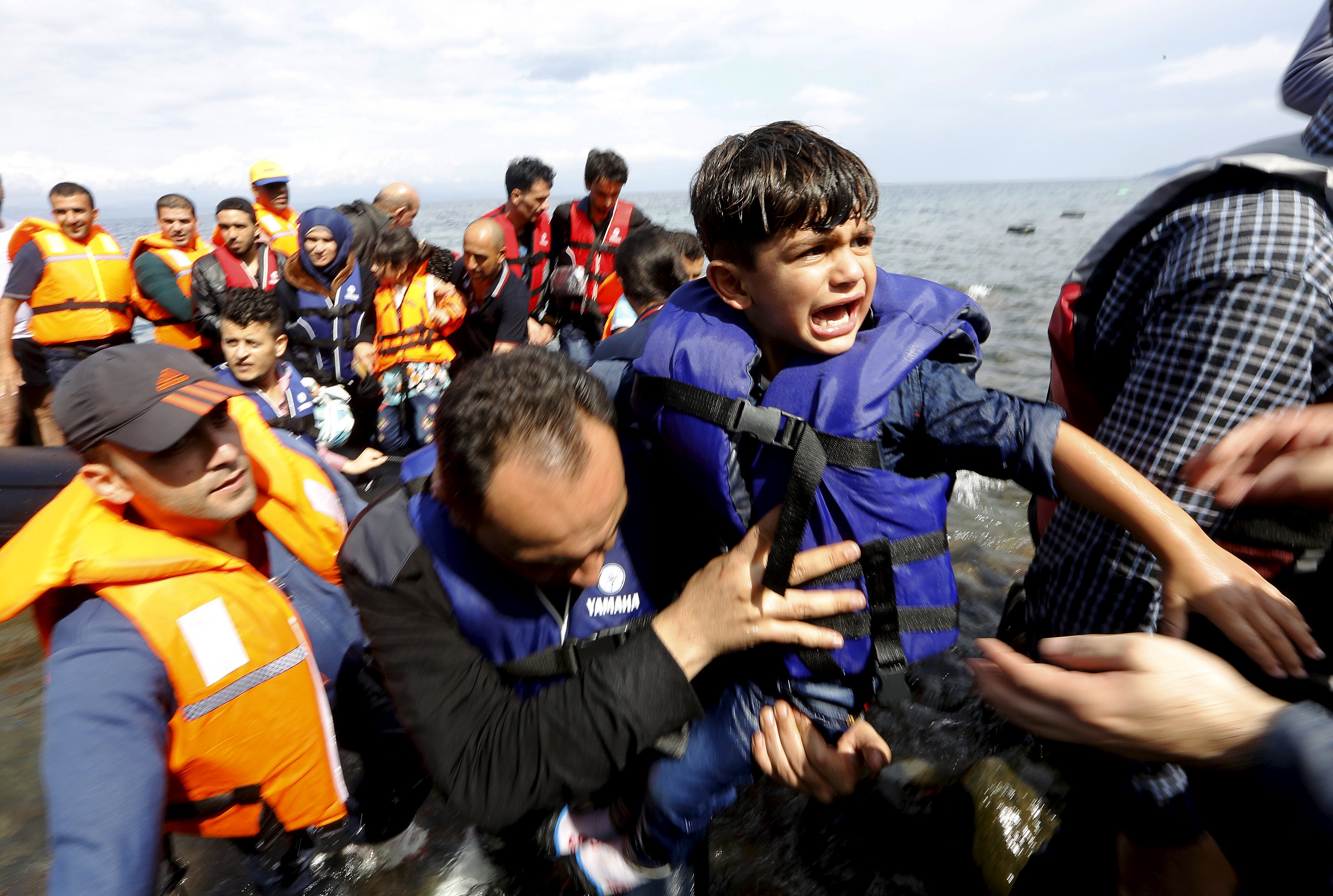 A Syrian refugee child is carried off an overcrowded dinghy on the Greek island of Lesbos, after crossing a part of the Aegean Sea from Turkey to Lesbos September 24, 2015.  REUTERS/Yannis Behrakis