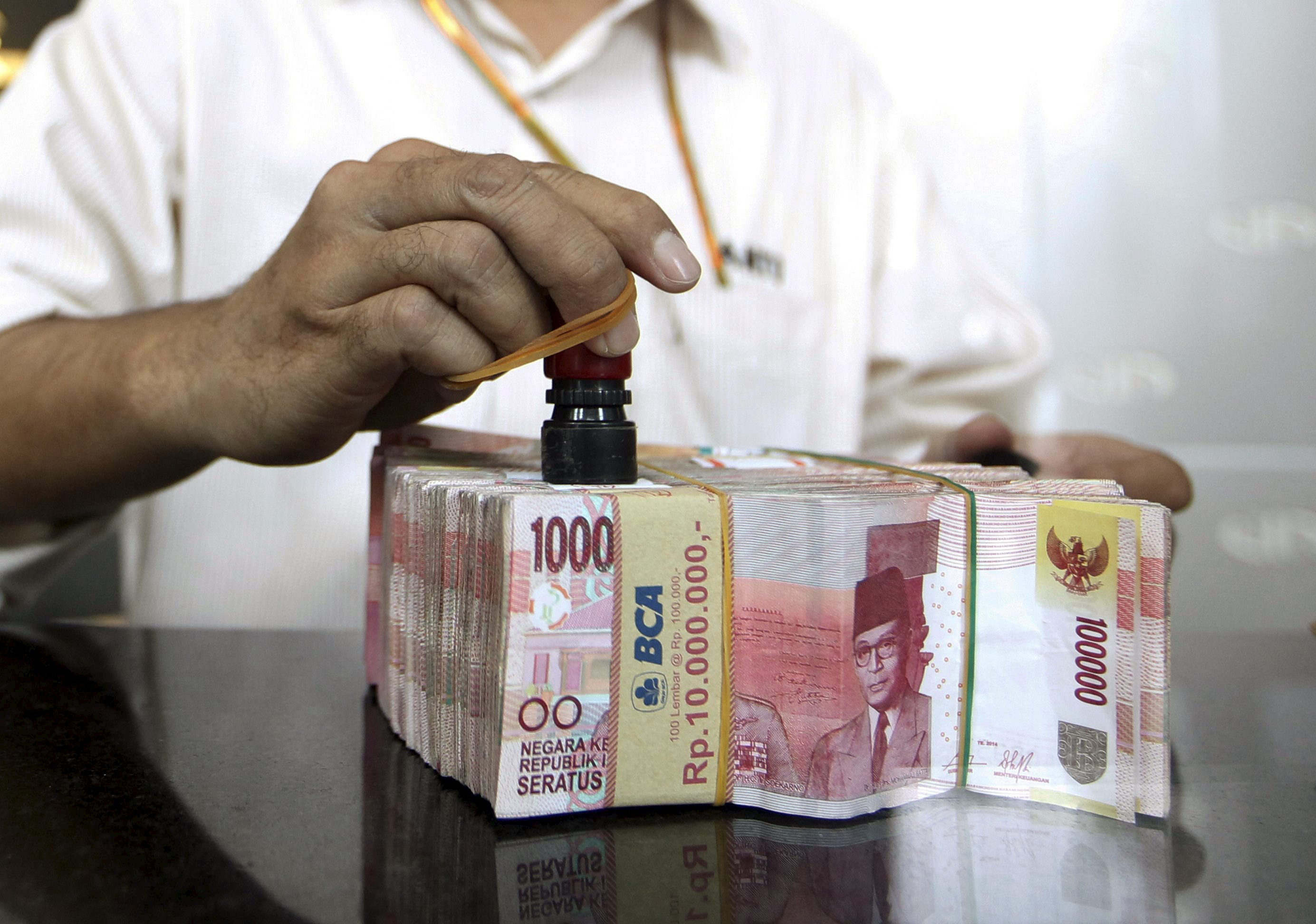 A money changer employee puts a stamp on Indonesia rupiah in Jakarta, September 29, 2015. Indonesian government officials on Tuesday announced a series of new economic stimulus measures, the second such package in three weeks, to help prop up the battered rupiah and revive growth in Southeast Asia's largest economy.  REUTERS/Nyimas Laula
