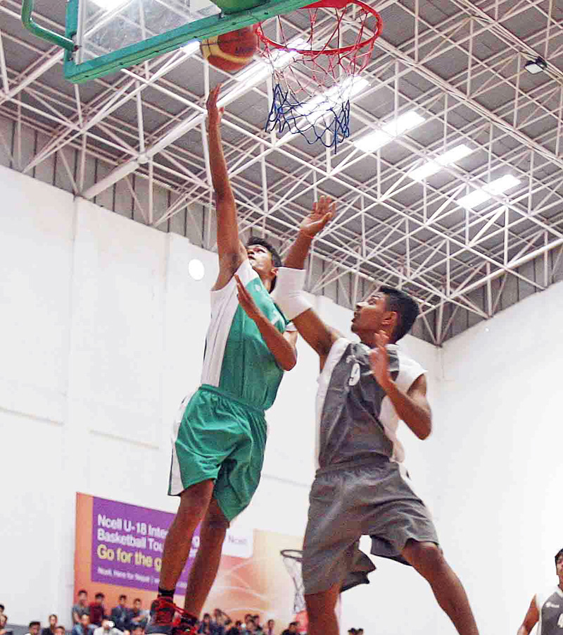 Shohart Shah (left) of Morgan jumps for a basket under pressure from Sujan Pariyar of White House during their Ncell U-18 Inter-college Basketball Championship at the nNepali Army Sports Complex in Lalitpur on Saturday.  Morgan won the match 53-24. Photo: Udipt Singh Chhetry/THT