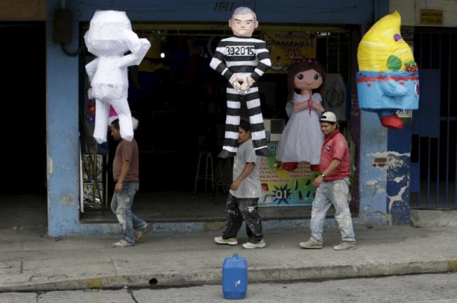 People walk past a pinata (C) representing former Guatemala's President Otto Perez wearing a jail uniform outside a pinatas store in downtown Guatemala City, September 4, 2015. REUTERS/Jorge Dan Lopez
