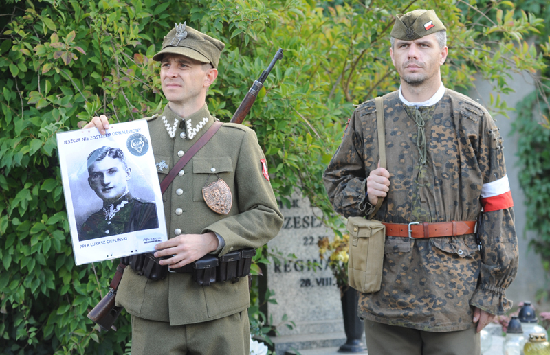 A man dressed in Polish Army WWII uniform holds a photo of a soldier with a writing 'I have not been found yet', during  the first burials of World War II heroes who were later secretly slain by the communists, at the Powazki cemetery in Warsaw, Poland, Sunday, Sept. 27, 2015. Remains of 35 Polish soldiers with bullet holes through the back of the skull were buried after being recently recovered from unmarked mass graves. (AP Photo/Alik Keplicz)