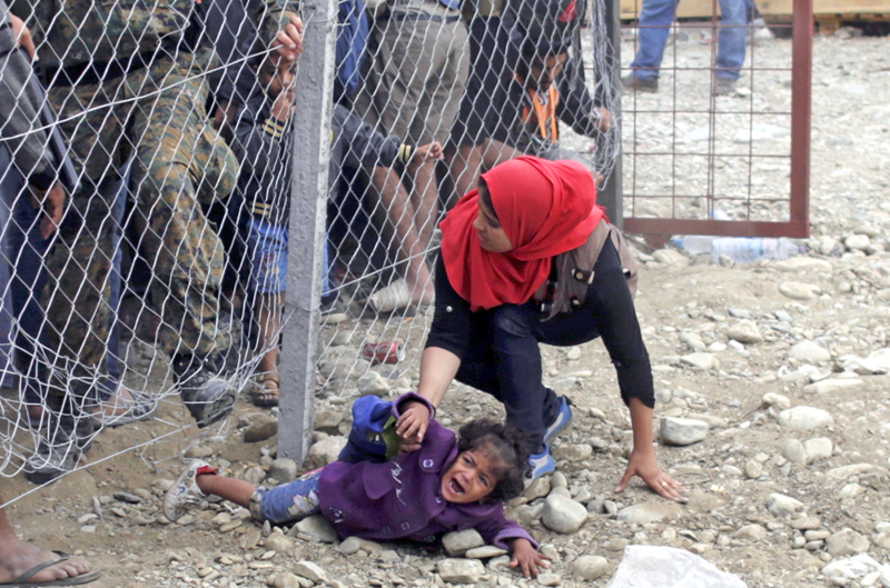 Police trying to stop migrants going under a fence to board a train at a station near Gevgelija, Macedonia, on Monday, September 7, 2015.  Thousands of migrants in Macedonia boarded trains on Sunday to travel north after spending a night in a provisional camp. Photo: Reuters
