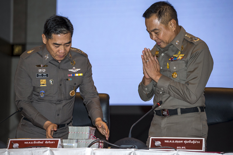 Thai national police chief Somyot Pumpanmuang (R) gestures as he hands over a reward to deputy police chief Chakthip Chaijinda before a news conference about the Bangkok blast which killed 20 people, including foreigners, at the Royal Thai Police headquarters in central Bangkok, Thailand, September 28, 2015. Police are offering a reward of 3 million baht (about $83,250) for the capture of the remaining suspects sought in connection with the case. Photo: REUTERS