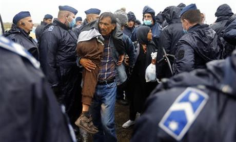 An Afghan man carries his son as he gets on a bus that will take them to the center for asylum seekers near Roszke, southern Hungary in Roszke, Thursday, Sept. 10, 2015. Leaders of the United Nations refugee agency warned Tuesday that Hungary faces a bigger wave of 42,000 asylum seekers in the next 10 days and will need international help to provide shelter on its border, where newcomers already are complaining bitterly about being left to sleep in frigid fields. Photo: AP