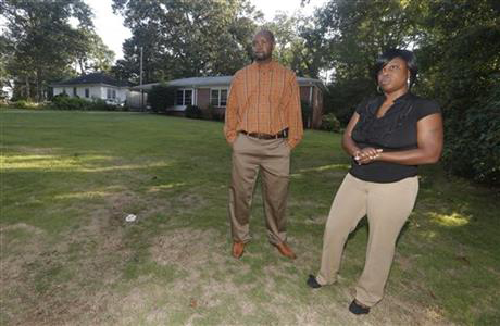 In this photo taken Thursday, Aug. 20, 2015, Gregory Bonds and his wife Sophia stand in front of a home in Atlanta, they previously lived in as they talks to a reporter about problems they had with a neighbor that forced them to move. In a lawsuit Bonds says a white neighbor, Roy Turner Jr., began yelling threats and racial slurs the day they moved in in February 2012.