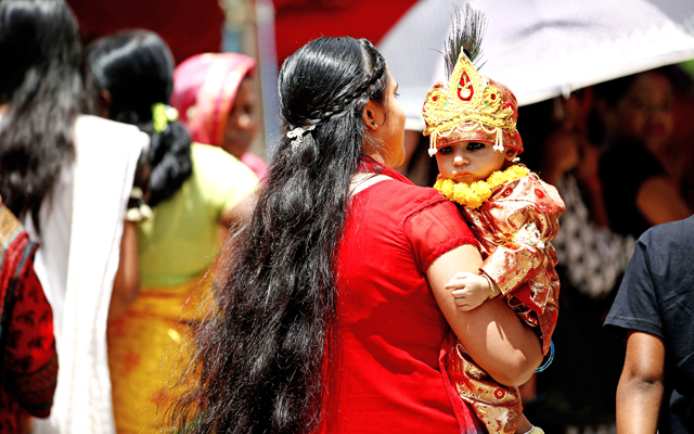 A woman carrying her child dressed as Lord Krishna during Krishna Janmasthami at Budhanilkantha in Kathmandu on Saturday. Photo: Skanda Gautam